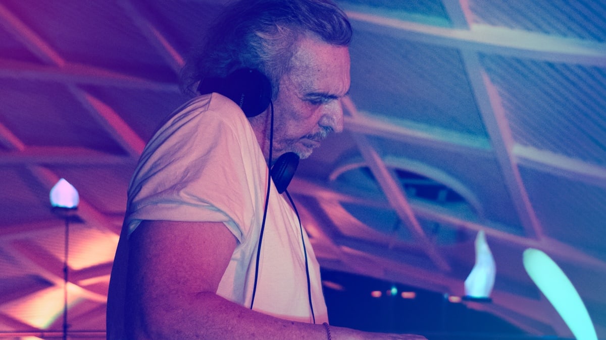 Frank N. steht mit Kopfhörern am Mischpult und konzentriert sich bei farbigem Licht auf elektronische Musik.